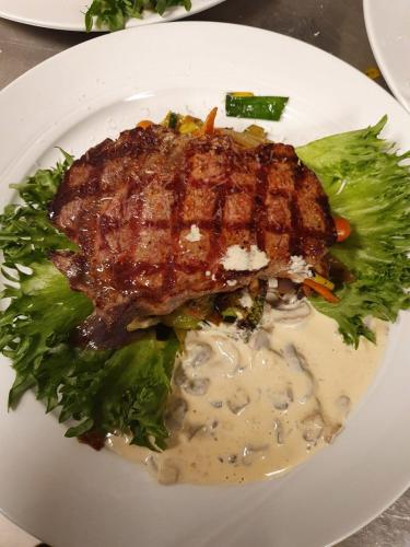 a plate of food with a piece of meat and broccoli at HOTELLMILANO AS in Mosjøen
