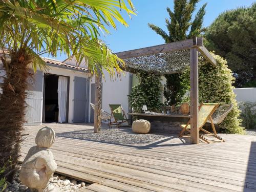 um deque de madeira com uma mesa e uma pérgola em Derrière la plage : suite, patio et pergola em Le Bois-Plage-en-Ré