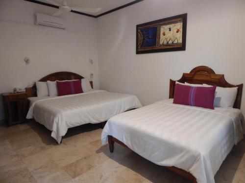 a bedroom with two beds with white and red pillows at Hotel Rockaway in Puerto Escondido