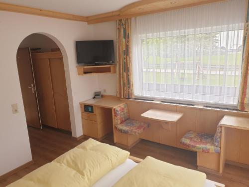 a room with a bed and a desk and a window at Haus Hubertus in Mieders