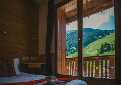 a bedroom with a large window with a mountain view at Hôtel Les Grangettes in Méribel