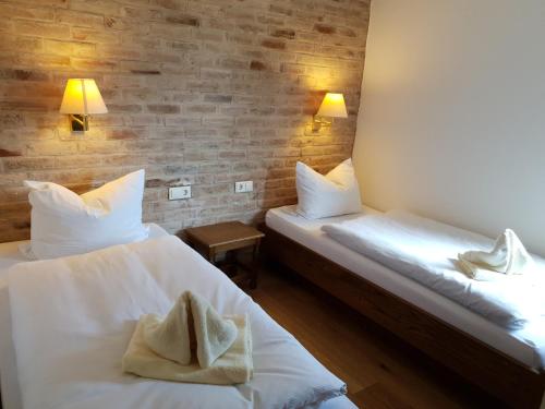 2 camas en una habitación con sábanas y almohadas blancas en Landhaus Akazienhof, en Nordstemmen