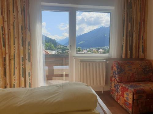 a bedroom with a bed and a large window with a view at Haus Hubertus in Mieders