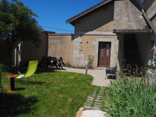 a yard with a green chair and a table at Le Gîte du haut in Châtillon-la-Palud