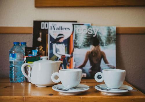 a table with two coffee cups and a magazine at Hôtel Les Grangettes in Méribel