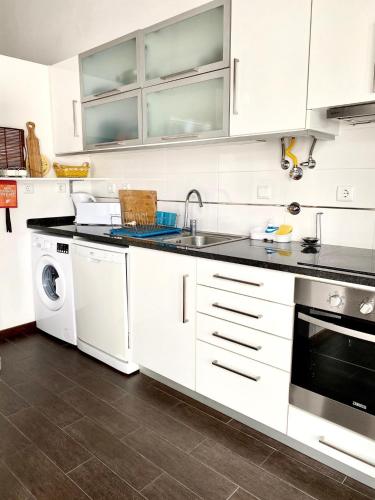 a white kitchen with a sink and a dishwasher at Casa Milheiras in Almeirim
