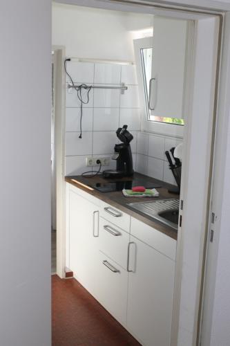 eine Küche mit weißen Schränken, einem Waschbecken und einem Fenster in der Unterkunft Berghaus Feldberg "Titiseeblick" in Bärental in Feldberg