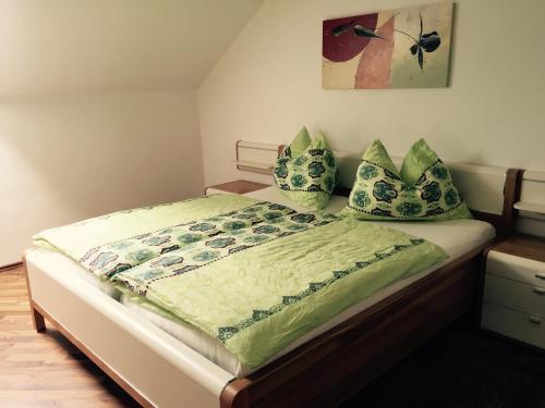 una camera da letto con letto, lenzuola e cuscini verdi di Das Ferienhaus ad Attersee am Attersee