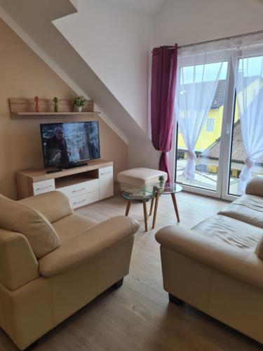 ein Wohnzimmer mit einem Sofa und einem TV in der Unterkunft Lessig Zimmer Vermietung in Schwabach
