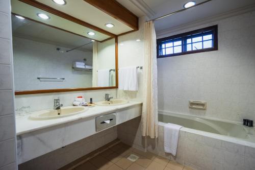 a bathroom with two sinks and a tub and a mirror at Berjaya Tioman Resort in Tioman Island