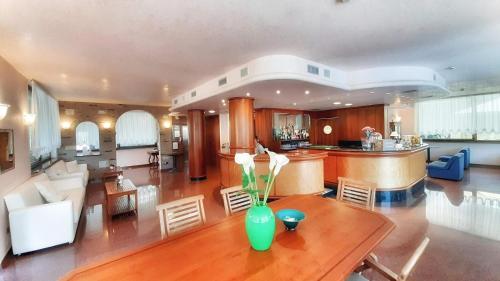 a kitchen and living room with a vase on a table at Hotel & Wellness Fra I Pini in Lignano Sabbiadoro