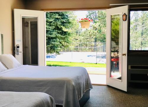 a bedroom with two beds and a sliding glass door at Bavarian Inn, Black Hills in Custer