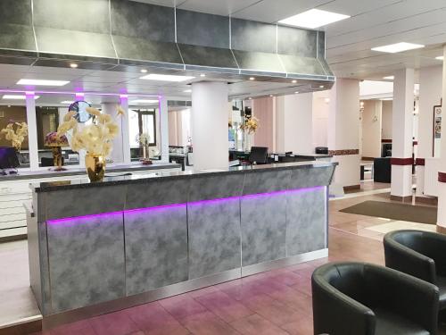 a lobby with a reception desk and chairs at Hôtel Angelic in Lourdes