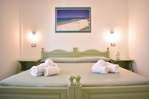 una camera da letto con due asciugamani su un letto con una spiaggia di Hotel Residence Ampurias a Castelsardo
