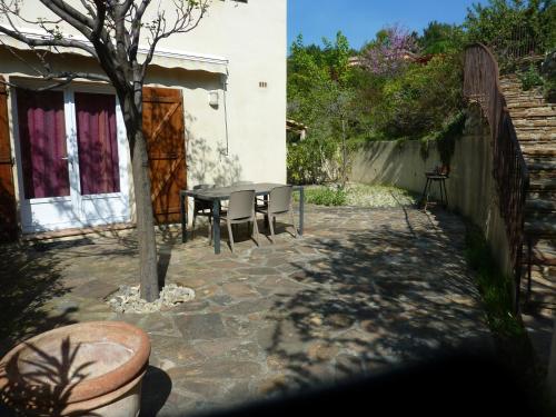 a patio with a table and chairs in a yard at La Thorie Ma maison de vacances in Clermont-lʼHérault