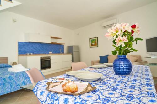 a table with a blue vase with a pastry on it at Maiori Dream House 1 in Maiori
