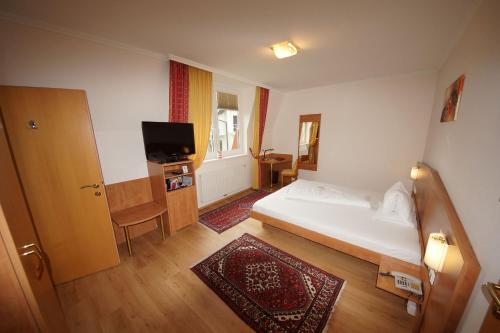 a hotel room with a bed and a television at Der Marienhof Hotel Garni in Graz