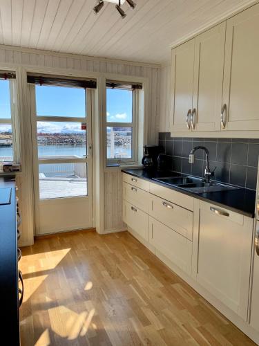 a kitchen with white cabinets and a view of the water at Rorbuene Svolvær Havn in Svolvær