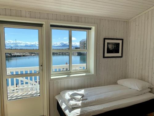 a bedroom with two windows and a bed and a balcony at Rorbuanlegget Svolvær Havn in Svolvær