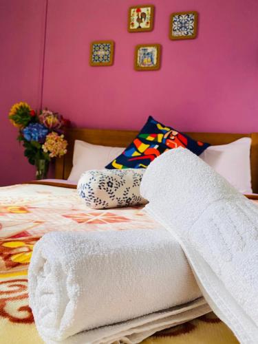 a bed with towels on it with a pink wall at Lisbon Prime Hostel & Rooms in Lisbon