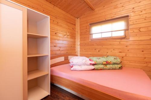 a small room with a bed in a wooden cabin at Paukščių Tako Svečių Namai in Šventoji