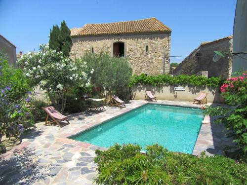 - une piscine dans une cour avec des chaises et un bâtiment dans l'établissement Le village-hôtes, à Sainte-Vallière