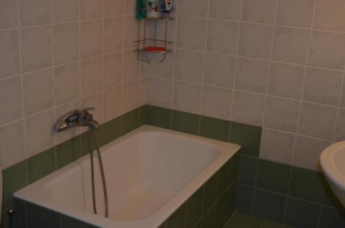a bath tub in a bathroom with green and white tiles at Christinas garden in Patra
