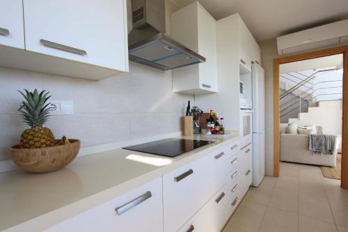 a kitchen with white cabinets and a pineapple on the counter at Can Lou-Casa con Caracter en Cullera in Faro de Cullera