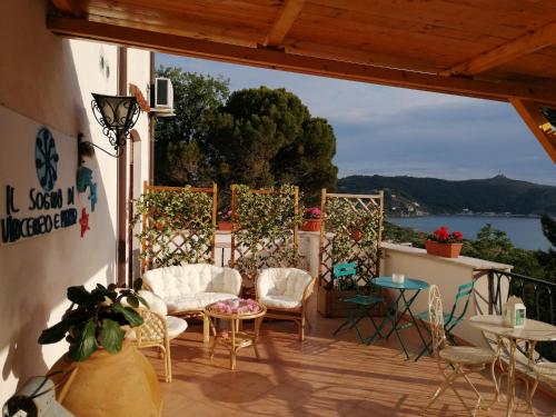 eine Terrasse mit Stühlen und Tischen und Blick auf das Wasser in der Unterkunft Il Sogno di Vincenzo e Maria in Palinuro