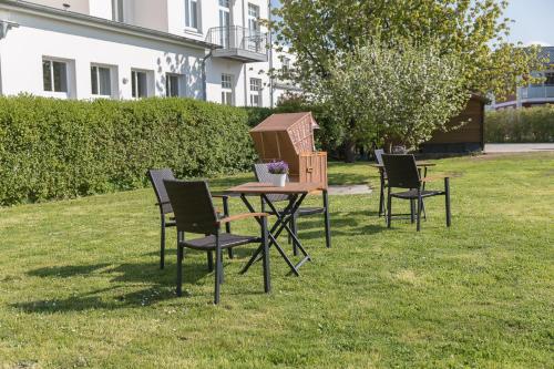 una mesa con sillas y una casa de pájaros en el césped en Villa Vineta, en Kühlungsborn