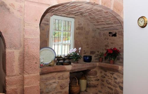 Baño de piedra con lavabo y ventana en Chambres d'Hôtes La Roumec, en Escandolières