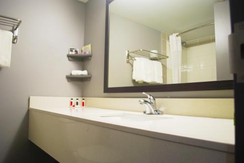 a bathroom with a mirror and a sink at Ramada by Wyndham Edmonton Yellowhead NW in Edmonton
