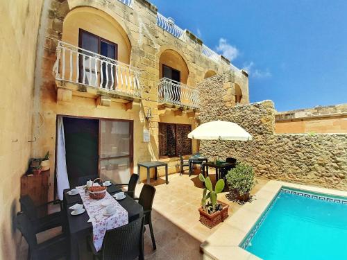 a patio with a table and a swimming pool at Blossom Farmhouses in Għasri