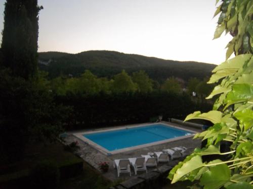 a swimming pool with white chairs around it at Chambres d'hôtes Maison Redon in Tour-de-Faure