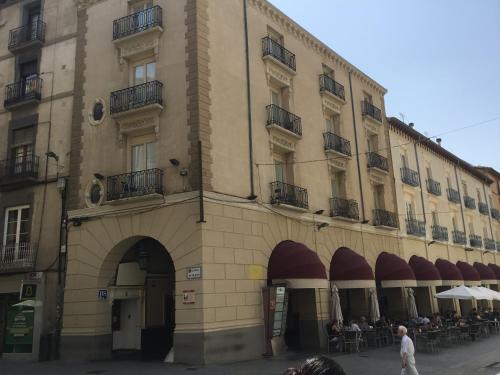 um grande edifício com pessoas sentadas fora dele em Hostal Rugaca em Huesca