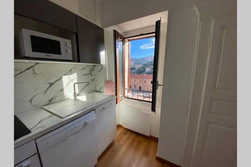uma cozinha com um lavatório, um micro-ondas e uma janela em FUNTANA NOVA em Piana