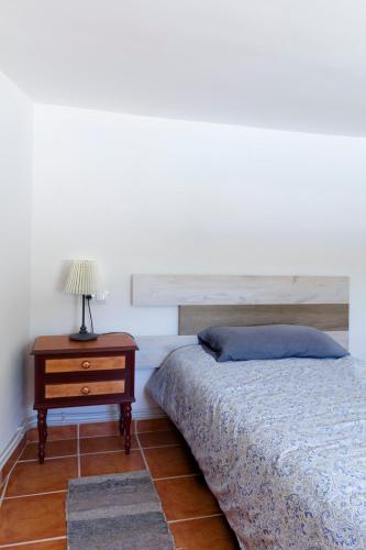 a bedroom with a bed and a table with a lamp at Casa del Arrabal in Montefrío