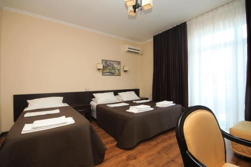 アナパにあるGuest House Uzhniy Beregのベッド2台、テーブルと椅子が備わるホテルルームです。