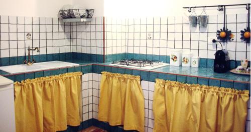 uma cozinha com fogão e cortinas amarelas em Daniela House em Santa Teresa di Riva