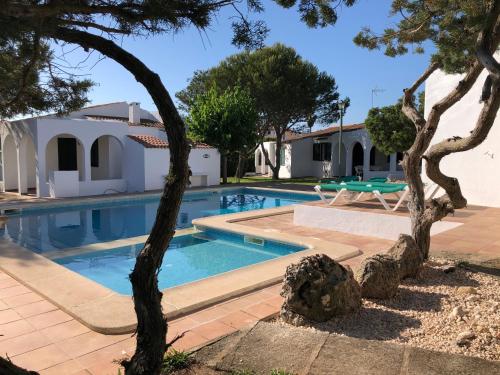 a swimming pool with trees in front of a house at Villas Las Alondras in Cala en Forcat