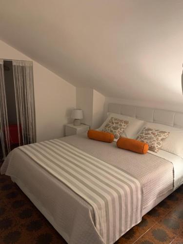 ein weißes Bett mit orangefarbenen Kissen im Schlafzimmer in der Unterkunft Dany’s house in Monopoli