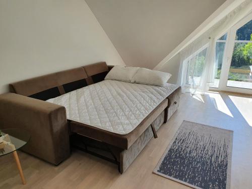 un letto in una camera con divano e finestra di Ošia Ošia VIP apartamentai a Palanga