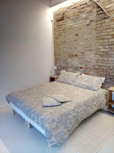 a bedroom with a brick wall and a bed at La Casa di Tara B&B Armonia e Natura in Recanati