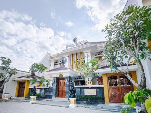 a white house with a tree in front of it at Collection O 3468 Ndalem Gusti Ayu in Yogyakarta
