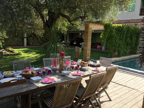 Una mesa con comida y un hombre parado frente a una piscina. en Villa Bonheur Vallespir, en Céret