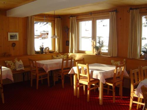 a dining room with two tables and chairs and windows at Pension Waldhof in Lech am Arlberg
