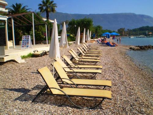 a row of lounge chairs and umbrellas on a beach at Andreas House in Dassia