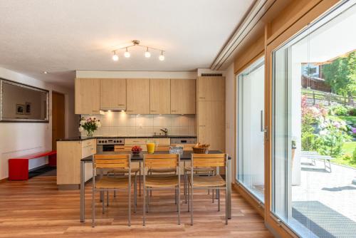 a kitchen with a table with chairs and a large window at Haus Alpine in Zermatt