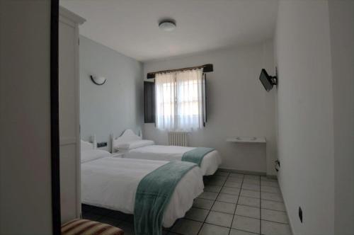 a hotel room with two beds and a mirror at El Refugio Hostería in Rabanal del Camino