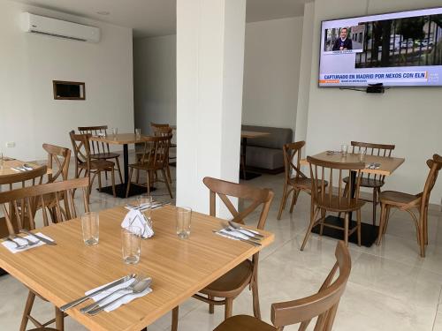 Hotel Metropolitano Plaza في فاليدوبار: مطعم بطاولات وكراسي خشبية وتلفزيون بشاشة مسطحة